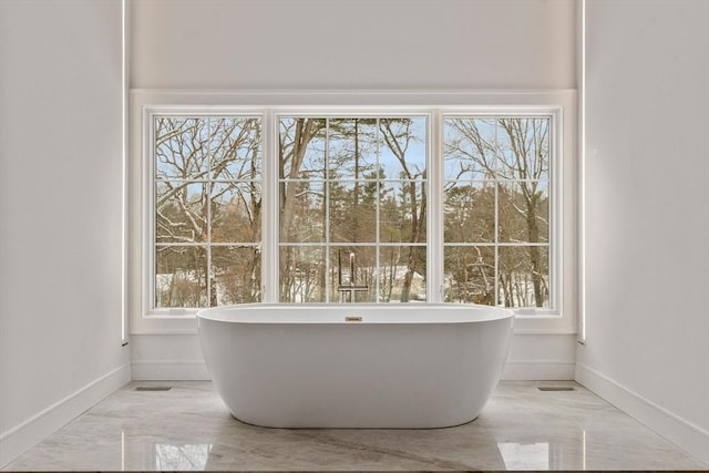 bathroom featuring a freestanding tub, marble finish floor, and baseboards