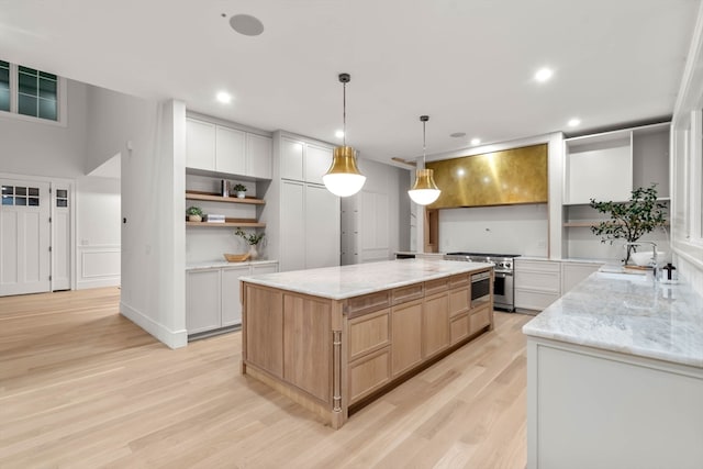 kitchen with stainless steel stove, a spacious island, white cabinets, light stone countertops, and light brown cabinetry