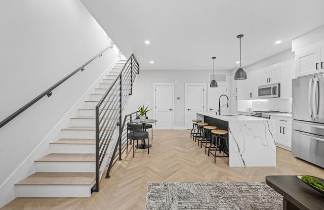 kitchen with stainless steel appliances, recessed lighting, a kitchen island with sink, a kitchen bar, and white cabinetry