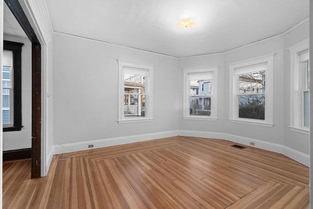 spare room featuring a wealth of natural light and hardwood / wood-style floors