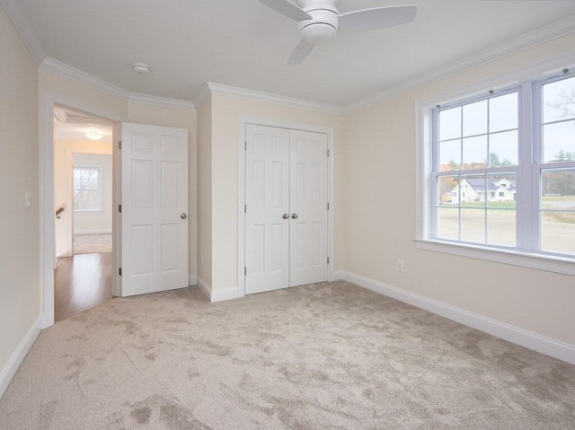 unfurnished bedroom with light carpet, ornamental molding, a closet, and baseboards