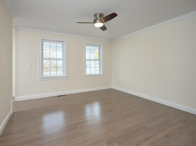 spare room featuring ornamental molding, a ceiling fan, baseboards, and wood finished floors