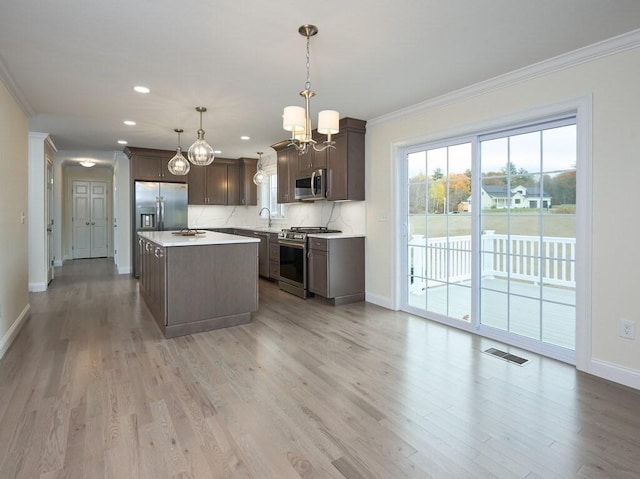 kitchen with stainless steel appliances, a sink, light countertops, a center island, and pendant lighting