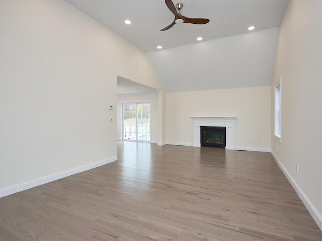 unfurnished living room with light wood-style floors, baseboards, a ceiling fan, and a glass covered fireplace