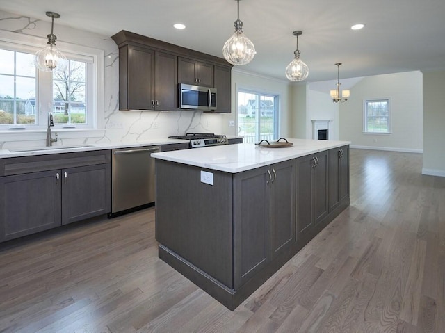 kitchen with stainless steel appliances, hanging light fixtures, a sink, and light countertops