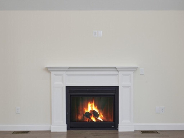 room details with a warm lit fireplace, baseboards, and visible vents