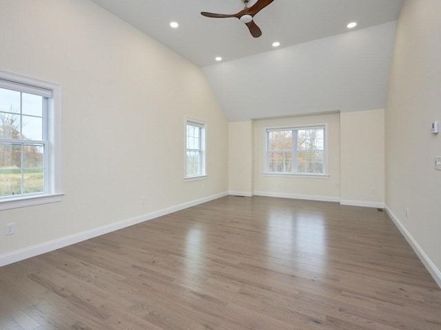 unfurnished room featuring a wealth of natural light, lofted ceiling, baseboards, and wood finished floors