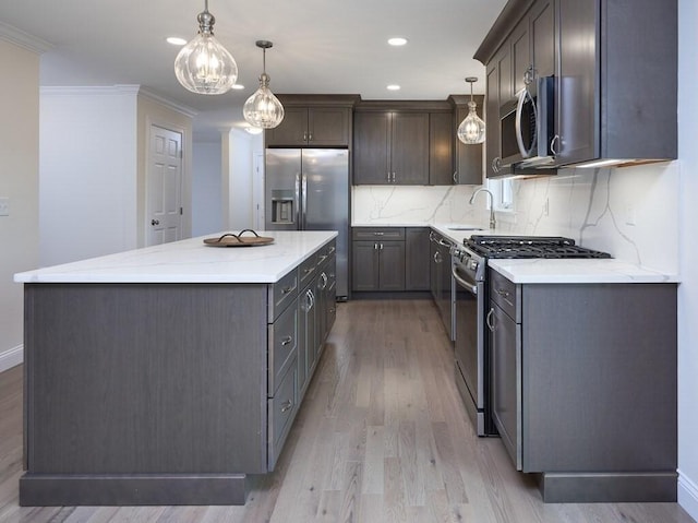 kitchen with hanging light fixtures, appliances with stainless steel finishes, crown molding, and a center island