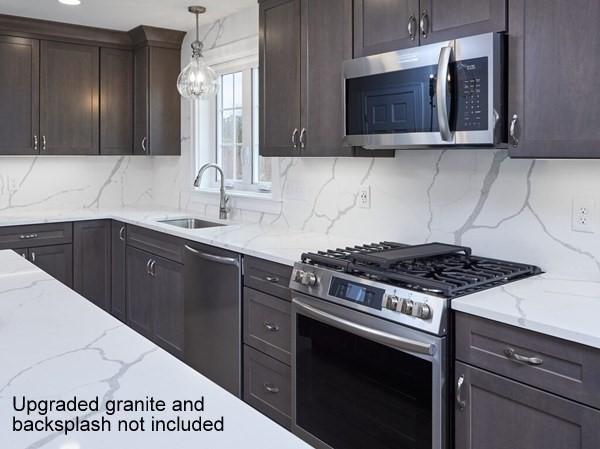 kitchen featuring hanging light fixtures, backsplash, appliances with stainless steel finishes, a sink, and light stone countertops