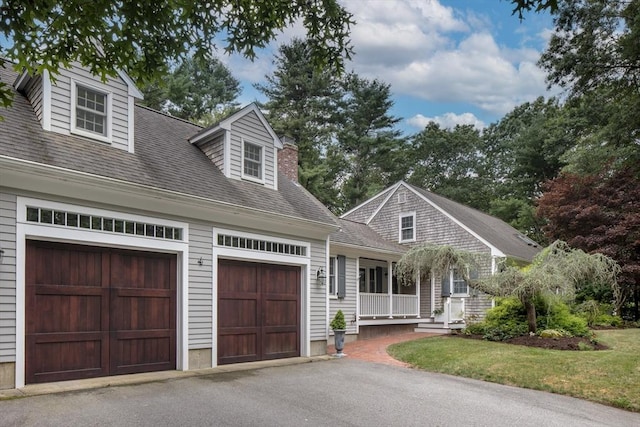 cape cod home with a front lawn, a porch, and a garage