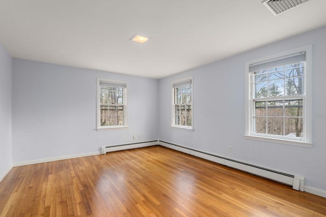 empty room with visible vents, baseboards, light wood-style floors, and a baseboard heating unit