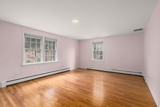 unfurnished room with baseboard heating, wood finished floors, and visible vents