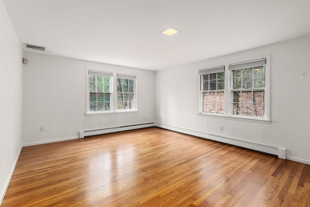 unfurnished room featuring baseboard heating, baseboards, visible vents, and wood finished floors