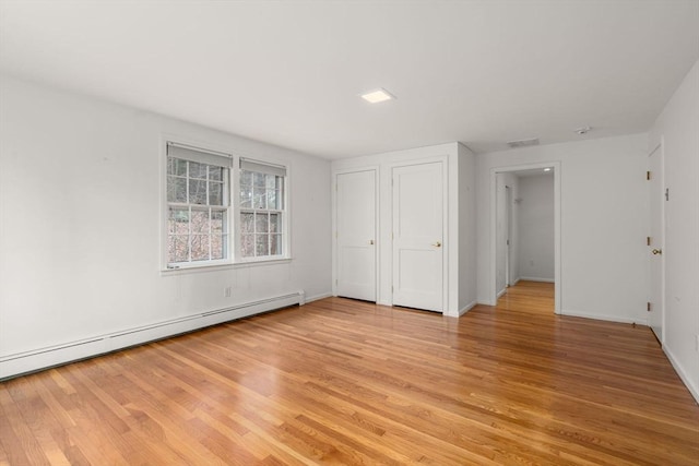 unfurnished bedroom with baseboards, visible vents, baseboard heating, and light wood-type flooring