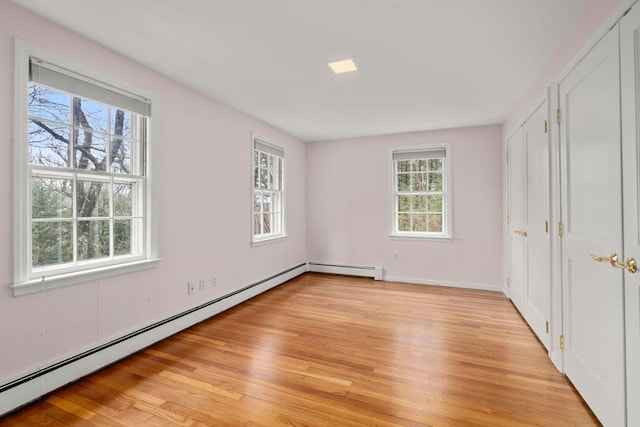 unfurnished bedroom featuring baseboards, a baseboard radiator, and light wood-style flooring