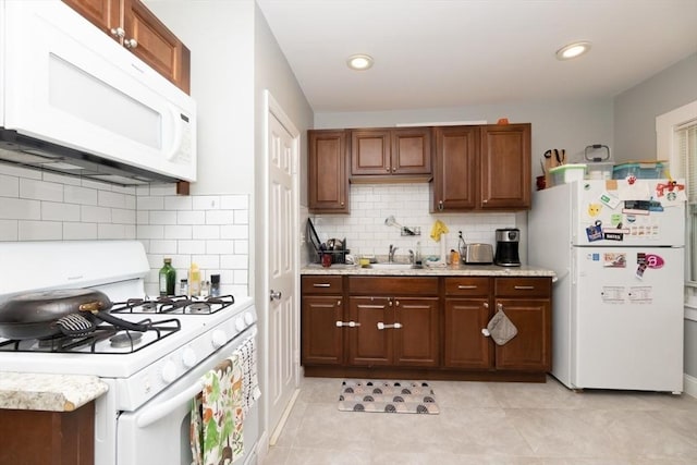 kitchen with decorative backsplash, light tile patterned flooring, white appliances, and sink