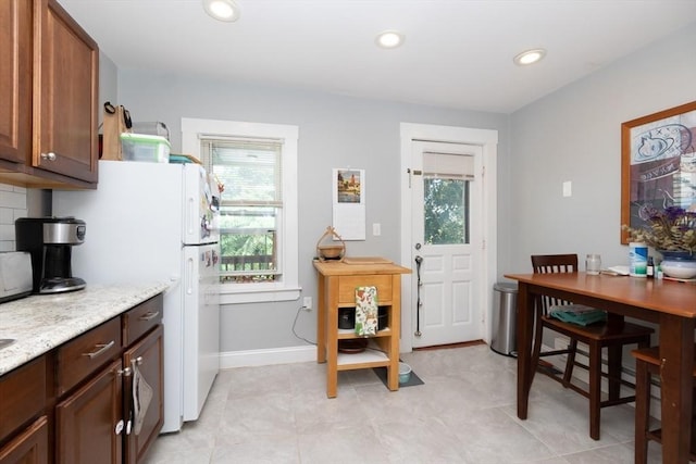 kitchen with decorative backsplash, light stone countertops, and white fridge