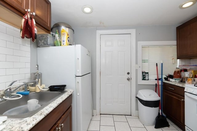 kitchen featuring light tile patterned floors, white appliances, tasteful backsplash, and sink