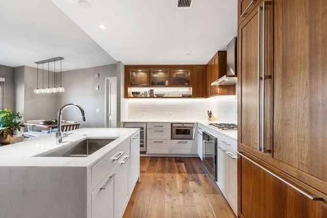 kitchen featuring a sink, stainless steel gas stovetop, light wood-style flooring, and light countertops