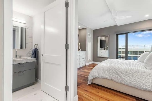 bedroom with baseboards, light wood-style flooring, recessed lighting, a sink, and ensuite bathroom