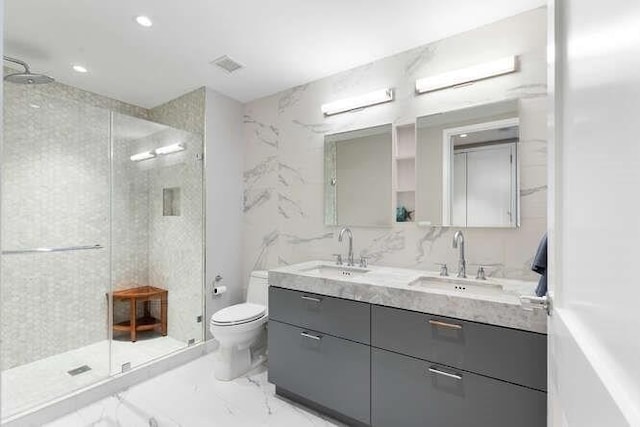 bathroom featuring marble finish floor, a stall shower, and a sink