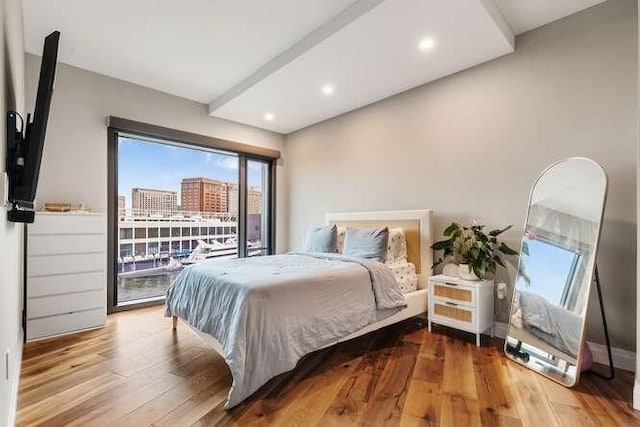 bedroom with a city view, recessed lighting, and wood finished floors