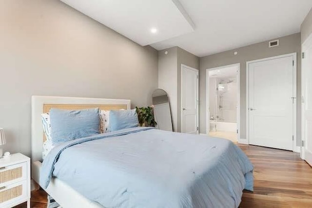 bedroom featuring visible vents, ensuite bathroom, and wood finished floors