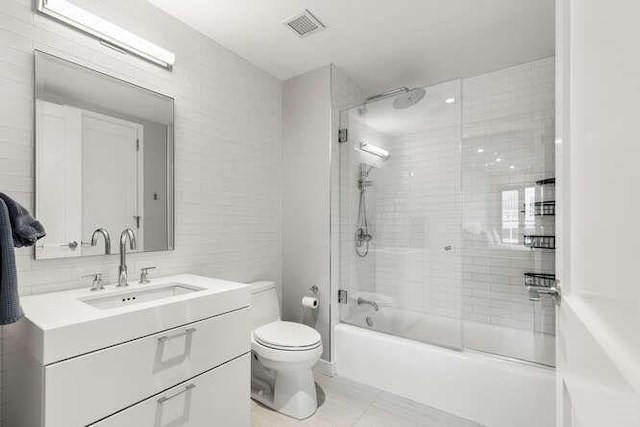 full bathroom with visible vents, toilet, tile walls, bathing tub / shower combination, and vanity