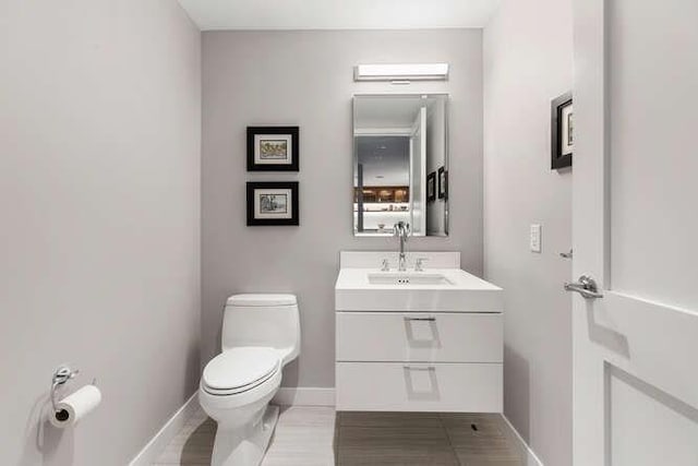 half bath with vanity, toilet, and baseboards