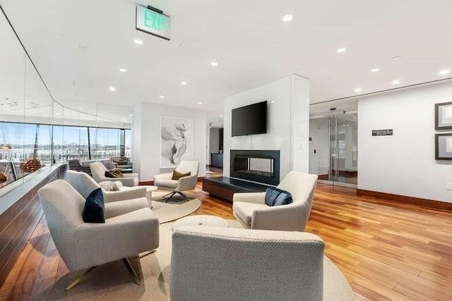 living room with recessed lighting, baseboards, a multi sided fireplace, and light wood-style flooring