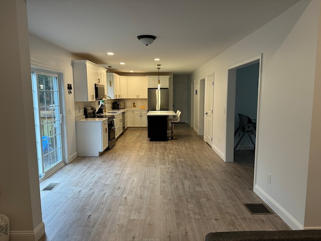 kitchen with a wealth of natural light, stainless steel appliances, white cabinetry, and hanging light fixtures