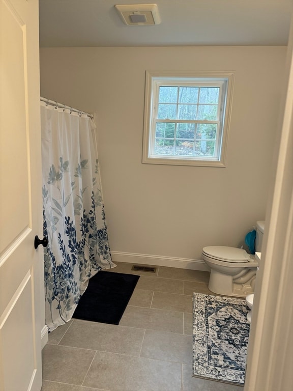 bathroom featuring tile patterned flooring, toilet, and curtained shower