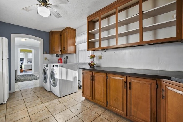 laundry area featuring cabinets, a textured ceiling, ceiling fan, light tile patterned floors, and independent washer and dryer