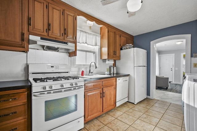 kitchen featuring light tile patterned floors, white appliances, a textured ceiling, and sink