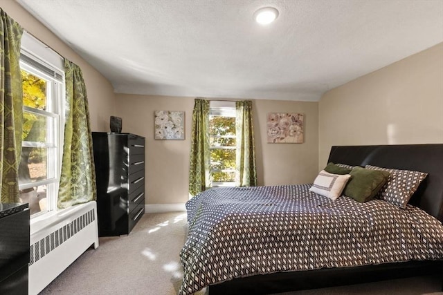 bedroom with light carpet, baseboards, and radiator