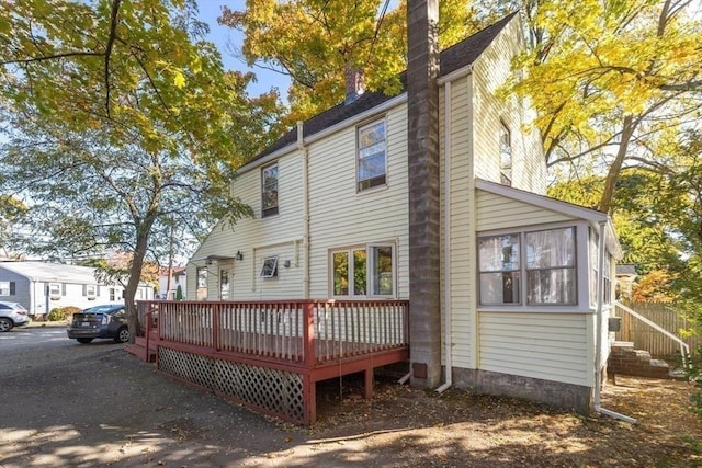 back of house with a deck and a chimney
