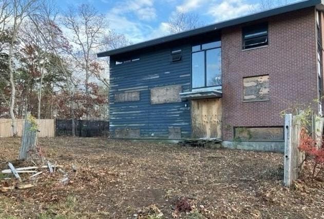 rear view of house with brick siding and fence