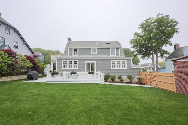 back of house with a chimney, a patio, and a shingled roof