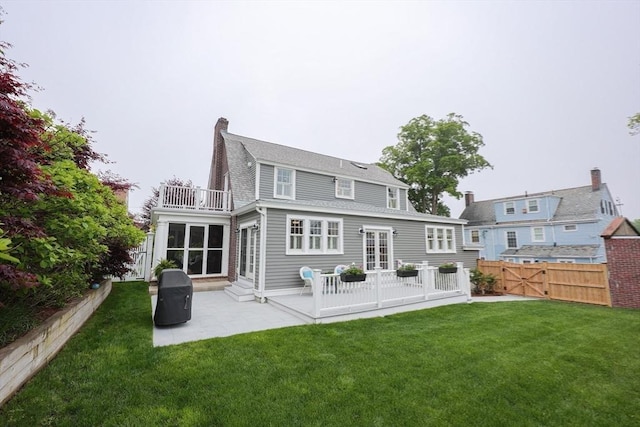 back of property featuring a patio, a balcony, a chimney, french doors, and a shingled roof