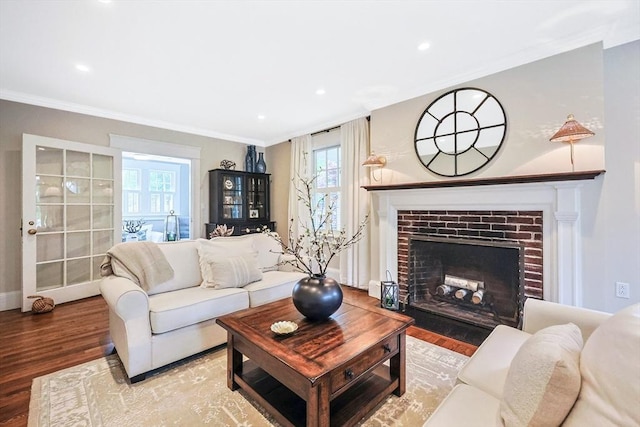 living area with a brick fireplace, wood finished floors, ornamental molding, recessed lighting, and baseboards