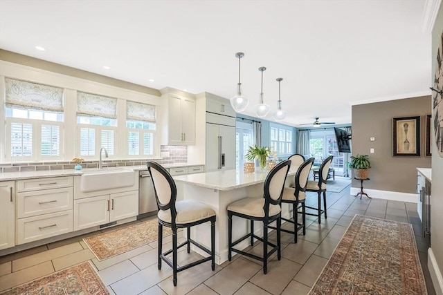 kitchen with a sink, built in refrigerator, a ceiling fan, a kitchen bar, and tasteful backsplash