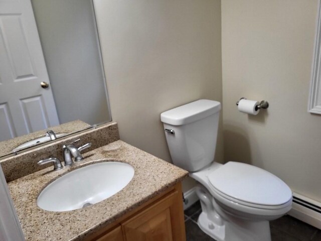 half bath with toilet, vanity, tile patterned flooring, and a baseboard heating unit