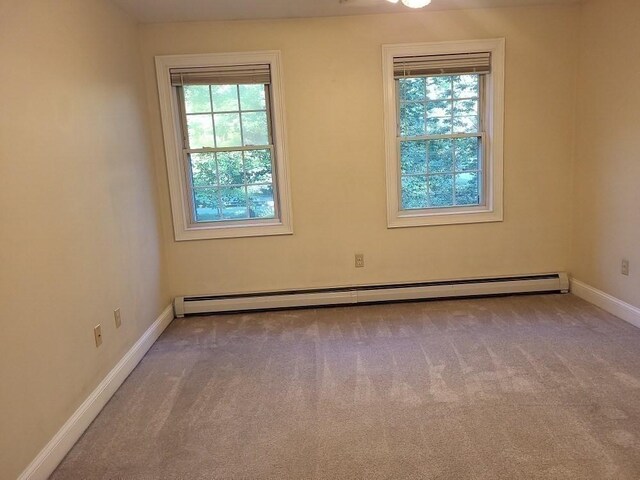 carpeted empty room with a baseboard radiator and baseboards