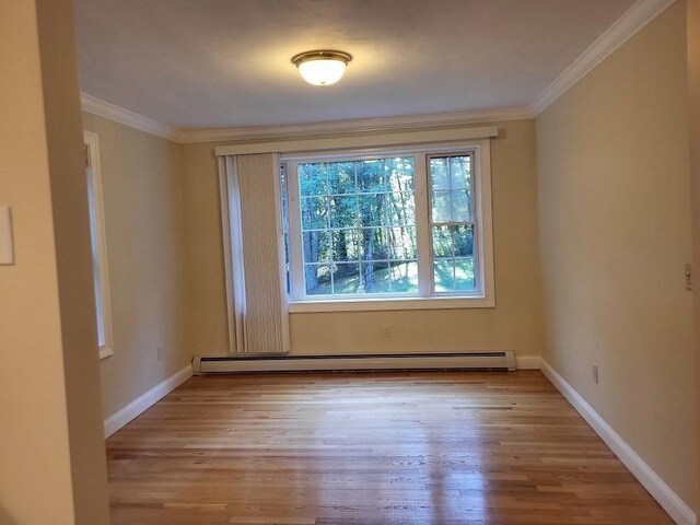 unfurnished room with baseboards, crown molding, wood finished floors, and a baseboard heating unit