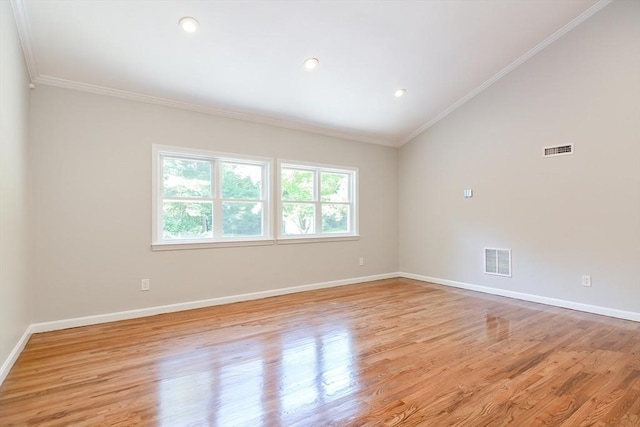 spare room with crown molding, vaulted ceiling, and light hardwood / wood-style floors