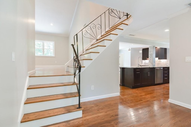 stairs with hardwood / wood-style floors, ornamental molding, and sink