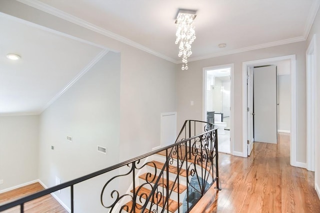 hall featuring crown molding, a notable chandelier, and light hardwood / wood-style floors