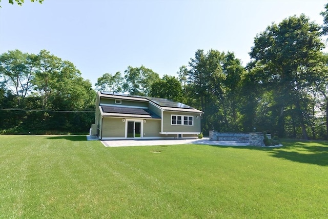 back of property with a yard, a patio area, and solar panels