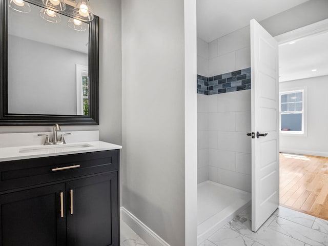 bathroom with vanity, tiled shower, hardwood / wood-style floors, and a healthy amount of sunlight