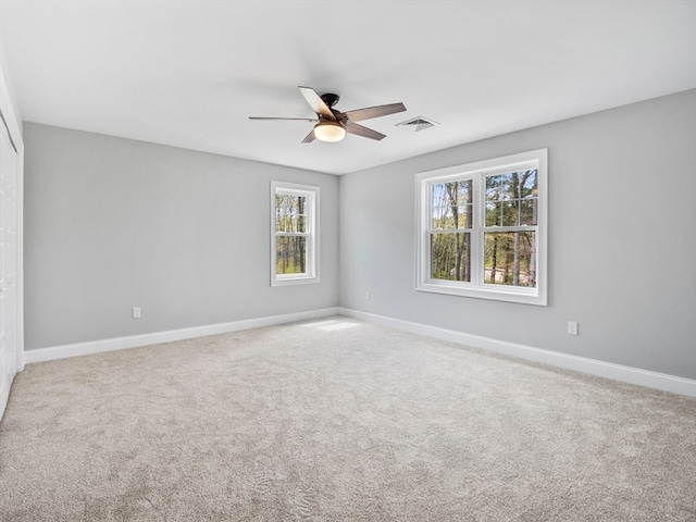 spare room with a wealth of natural light, carpet, and ceiling fan